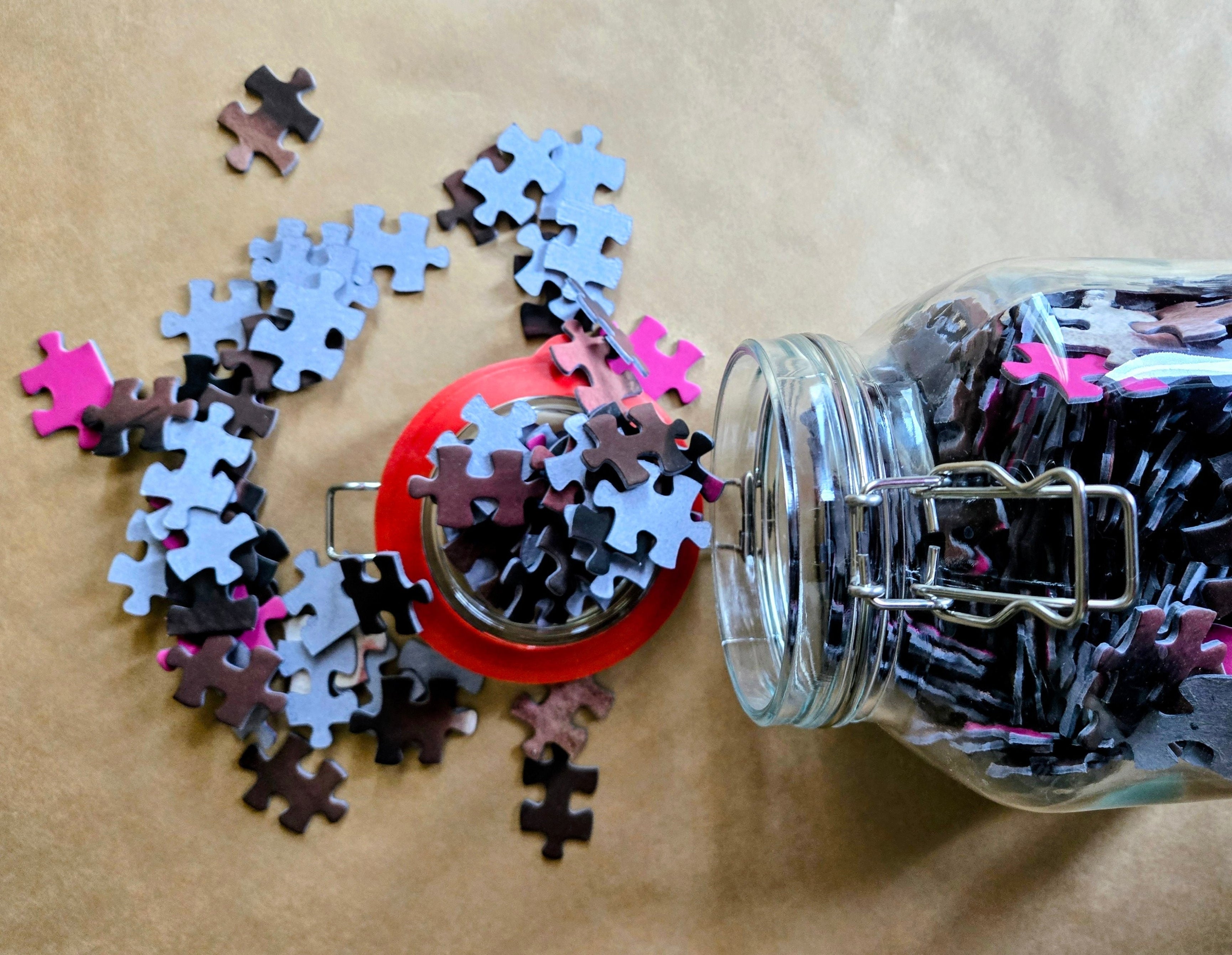 Jigsaw puzzle pieces spilling out of a jar on a brown surface