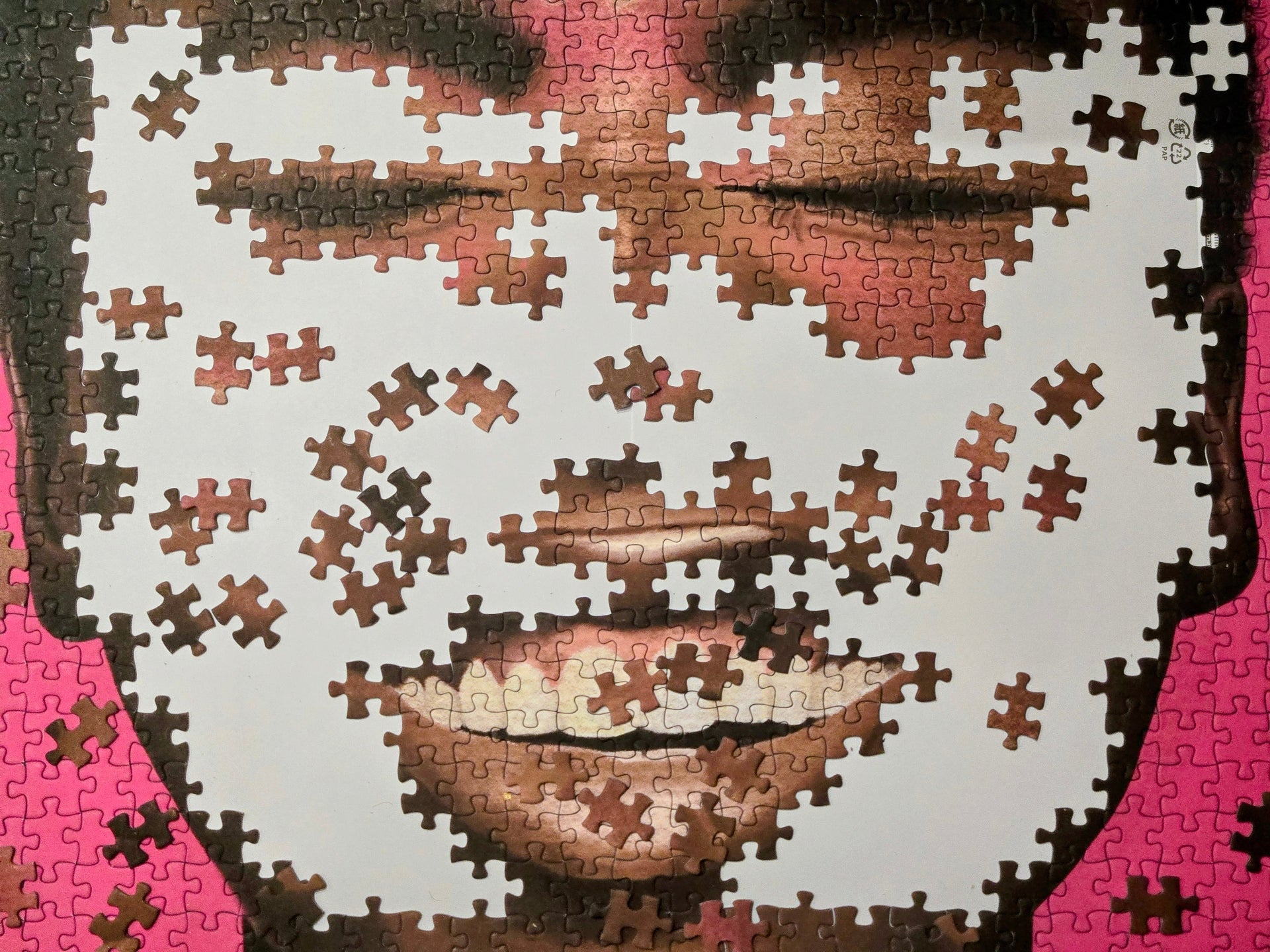 Jigsaw puzzle with a portrait of a person on a pink background